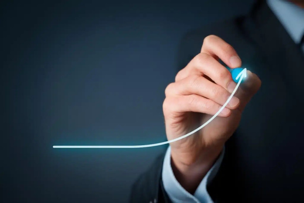 A businessman in a suit drawing a graph on a whiteboard.