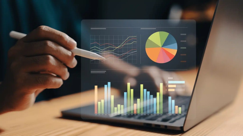 Image of a person using a laptop with a graph visible on the screen.